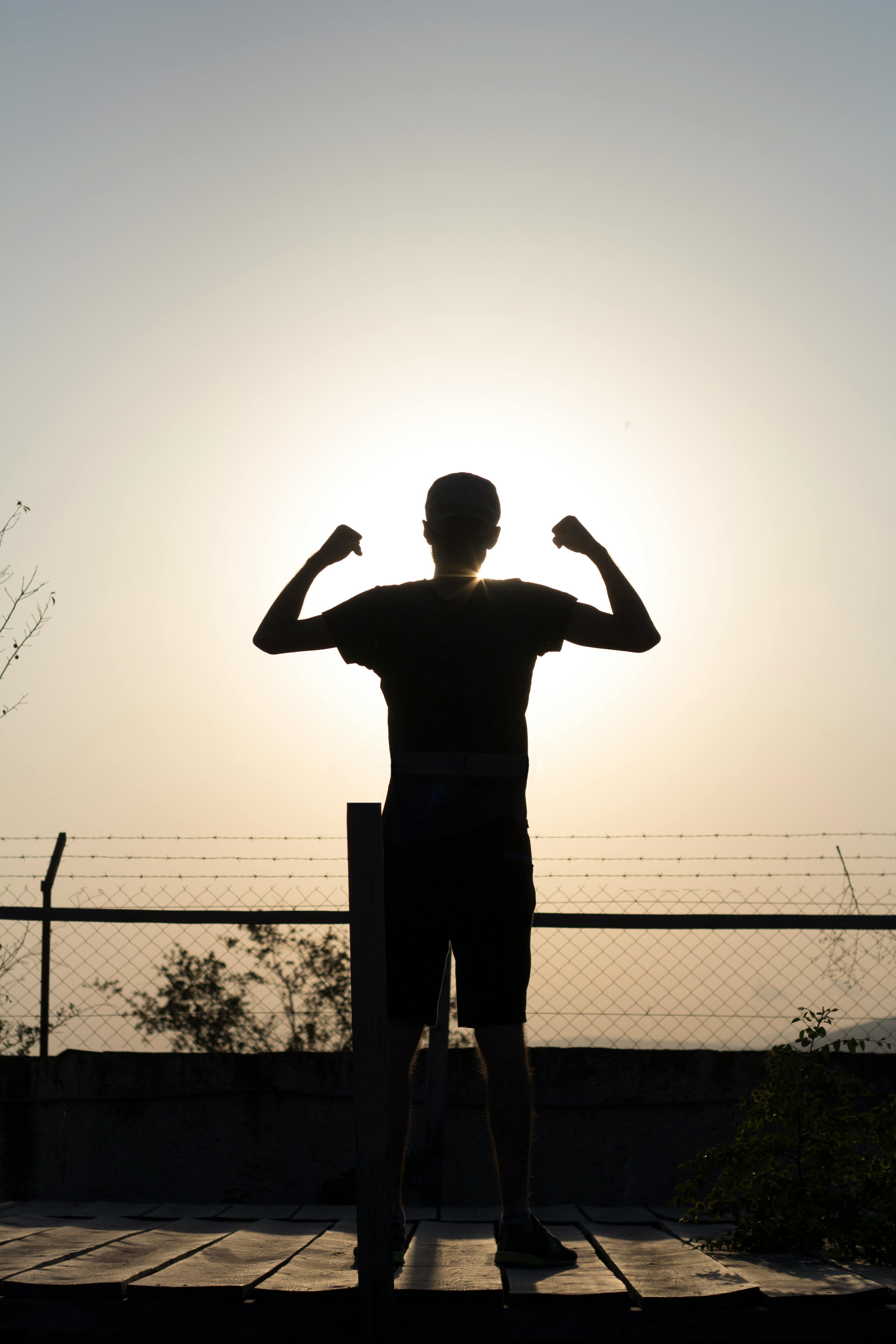 A silhouette of a person standing on a hill at sunrise, symbolising new energy